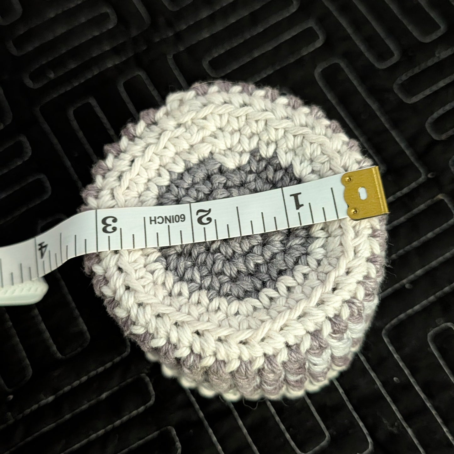 crochet item with a measuring tape on a textured black surface